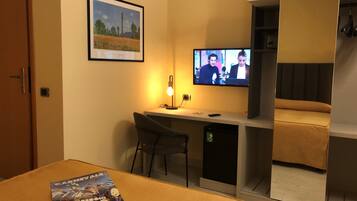 Une chambre d’hôtel comprenant un lit, un bureau avec une chaise, une télévision et une armoire.