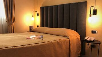 Una habitación de hotel con una cama grande, dos lámparas de noche, un teléfono junto a la cama y una mesita con lámpara.