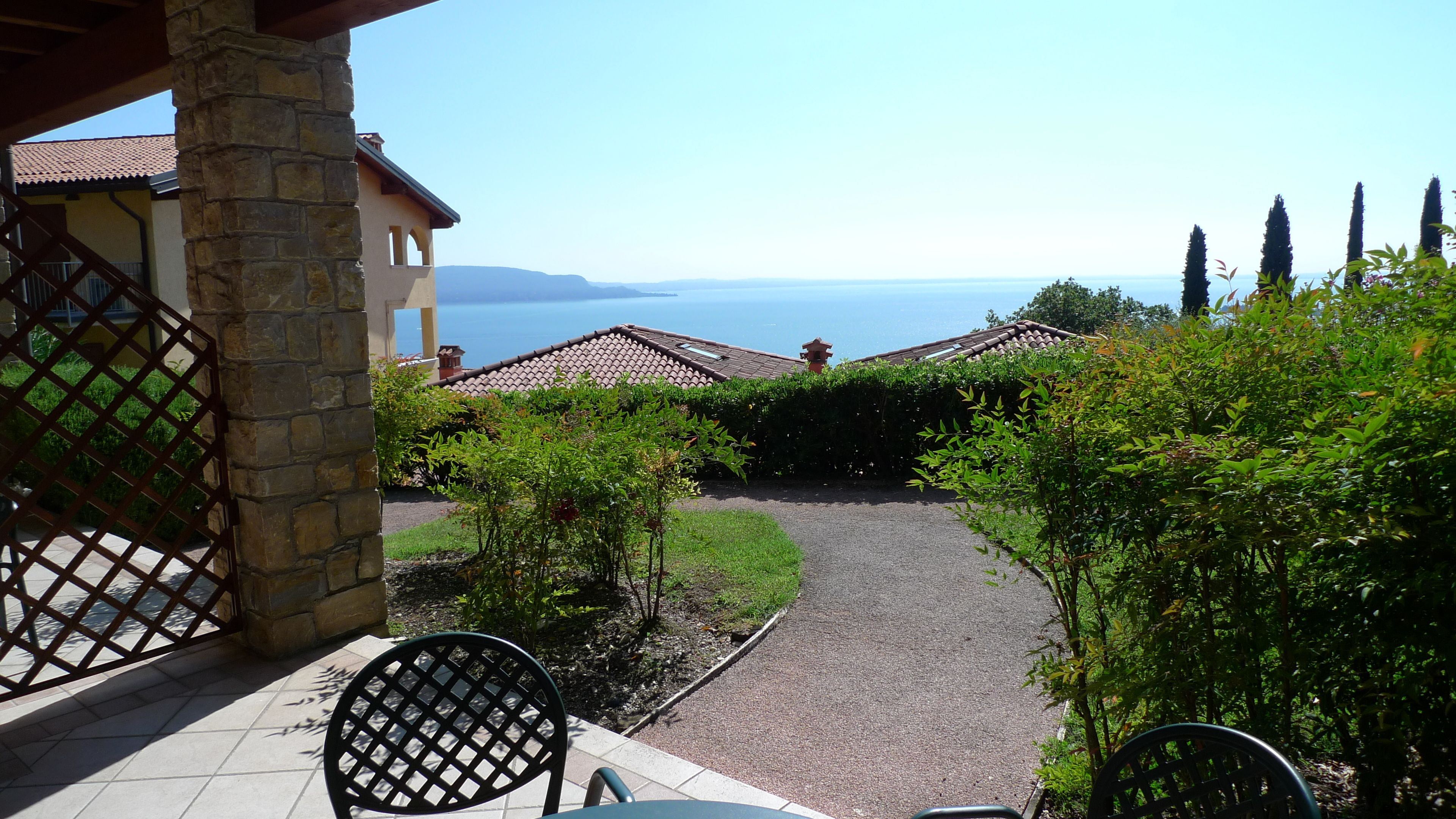 Una terraza con vista al mar, pilares de piedra y un sendero empedrado que lleva a una zona de estar.