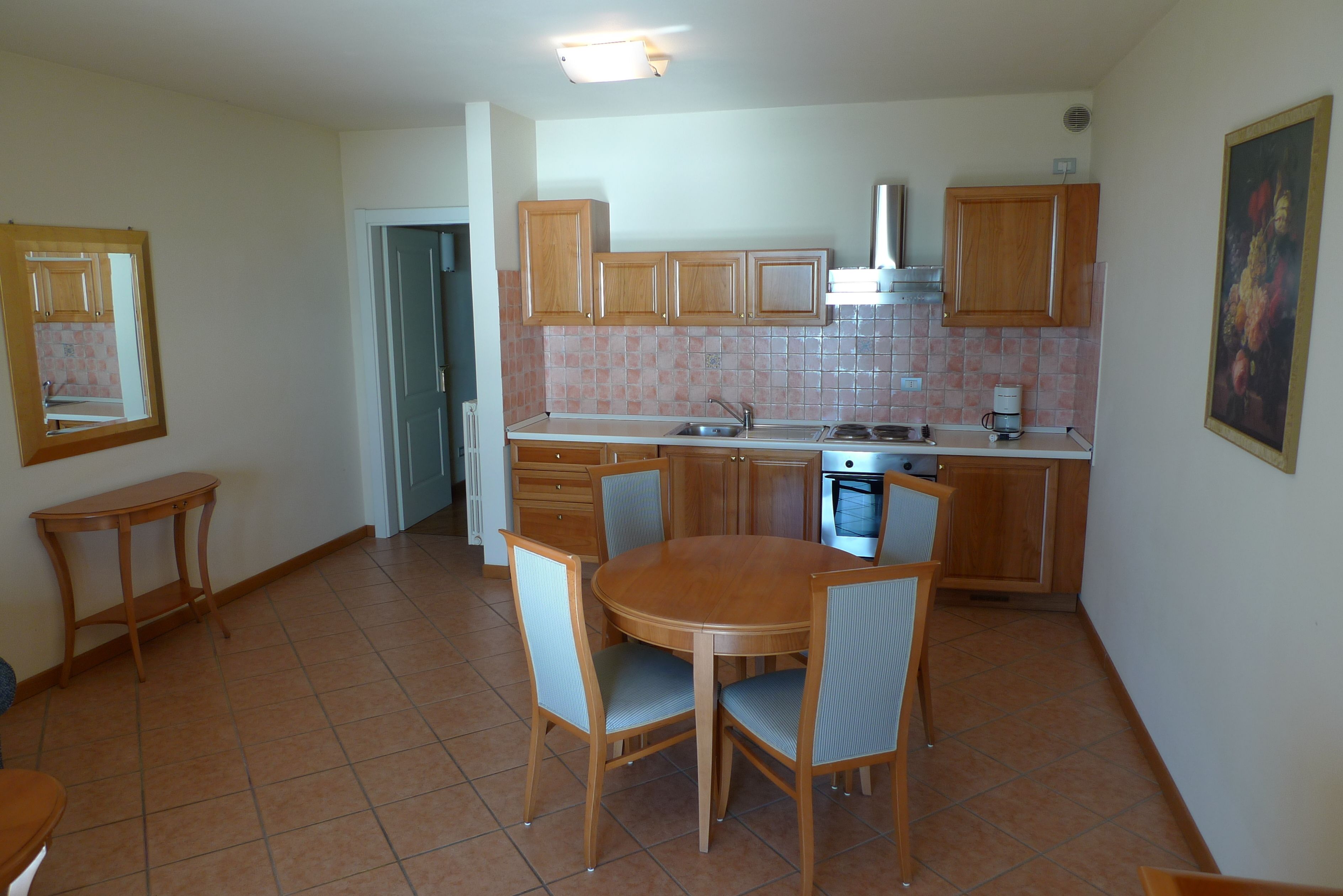 A kitchen with wooden cabinets, a dining table with chairs, and a tiled backsplash.