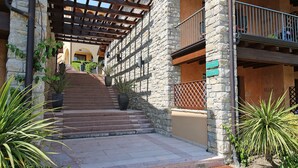 Un bâtiment en pierre avec un escalier en bois menant à une entrée abritée.