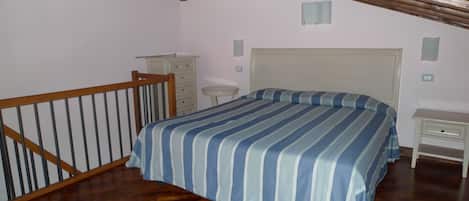 A bedroom with a wooden bed, a nightstand, a dresser, and a small table.
