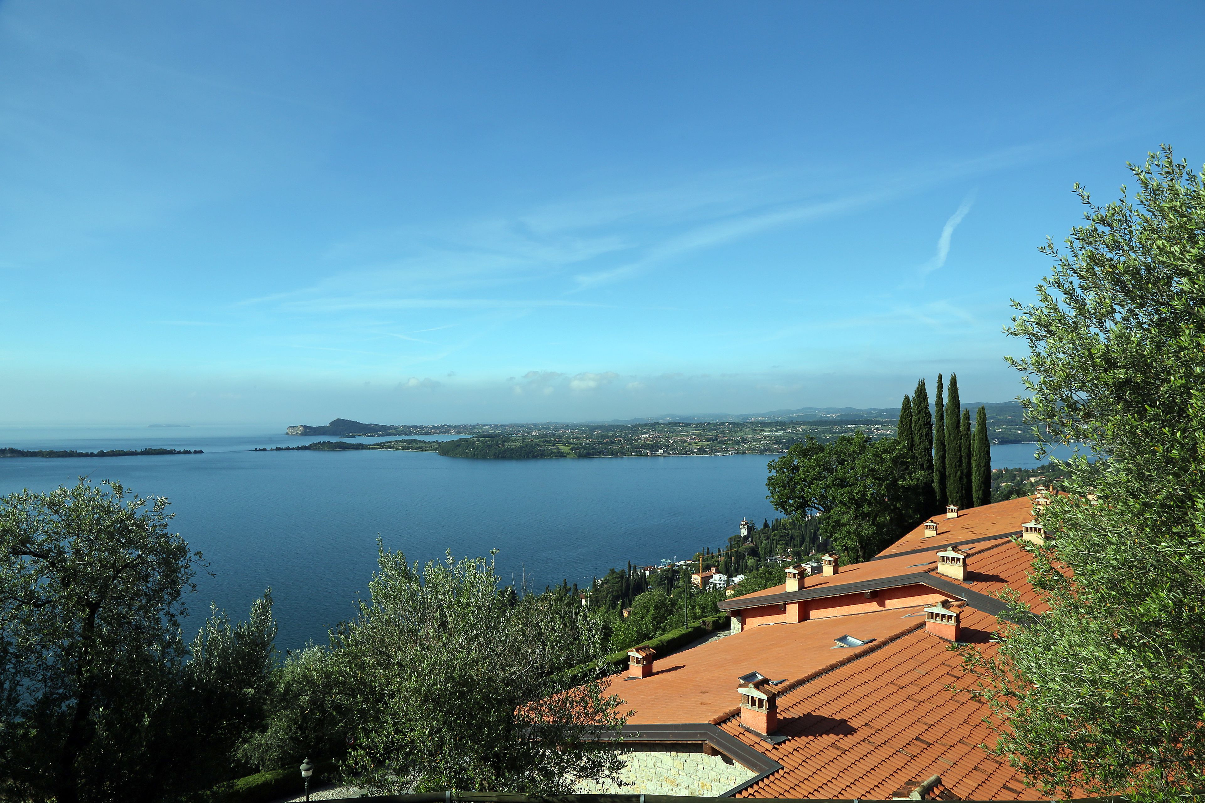 Blick auf die Küste mit Häusern mit Terrakotta-Dächern, einem klaren blauen Himmel und ruhiger See.