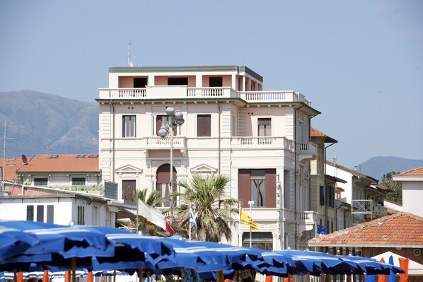 A multi-story building with balconies, a satellite dish, and flags. - Villa Tina (Viareggio)