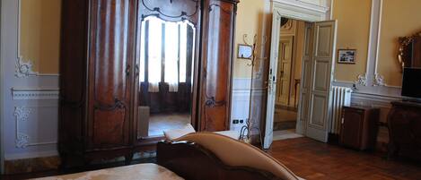 A bedroom with a large bed, a wooden wardrobe, and a mirror.