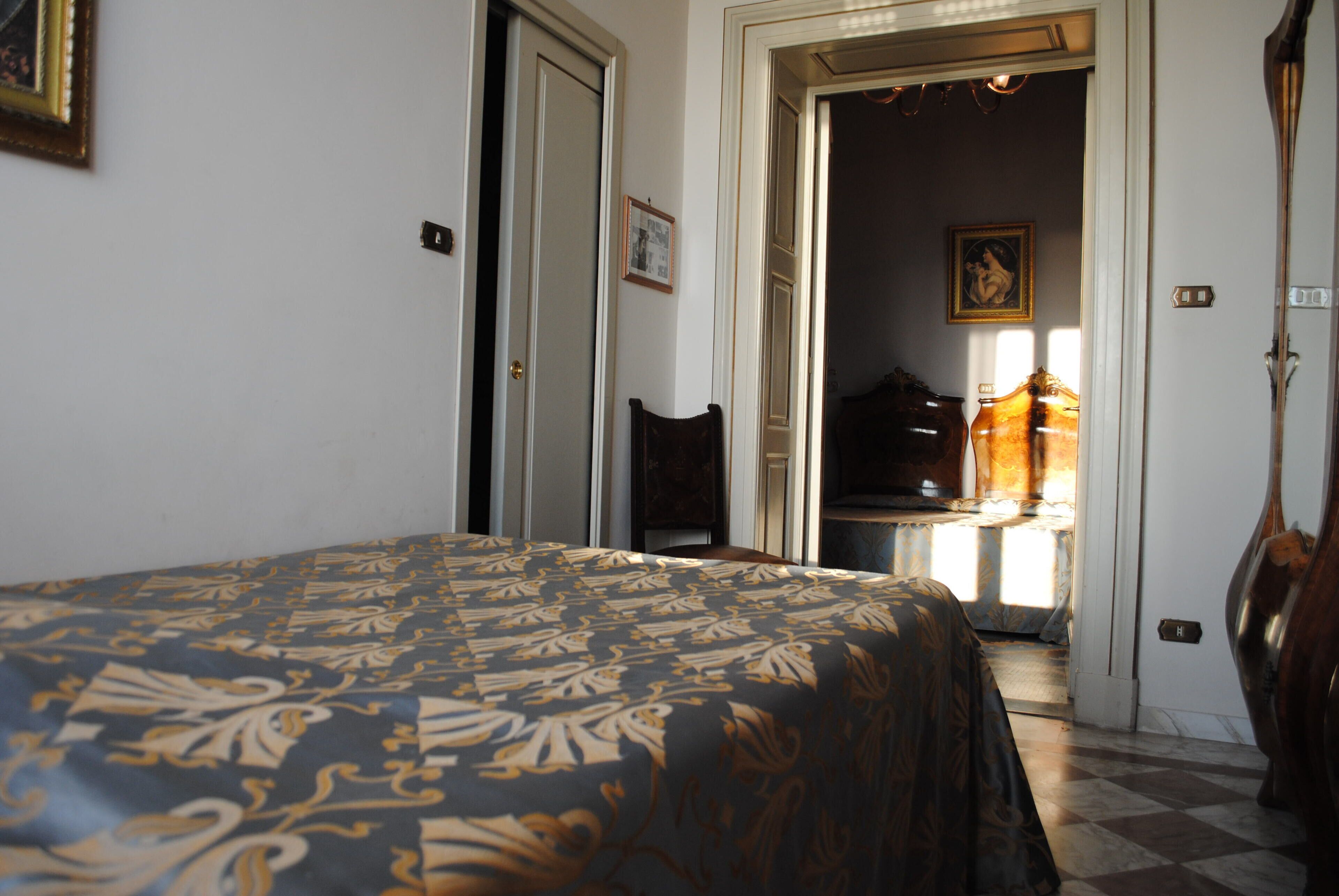 A bedroom with a bed, a chair, and a door leading to another room.