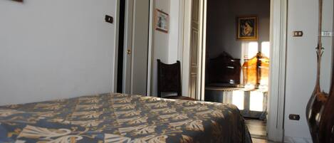 A bedroom with a bed, a chair, and a door leading to another room.