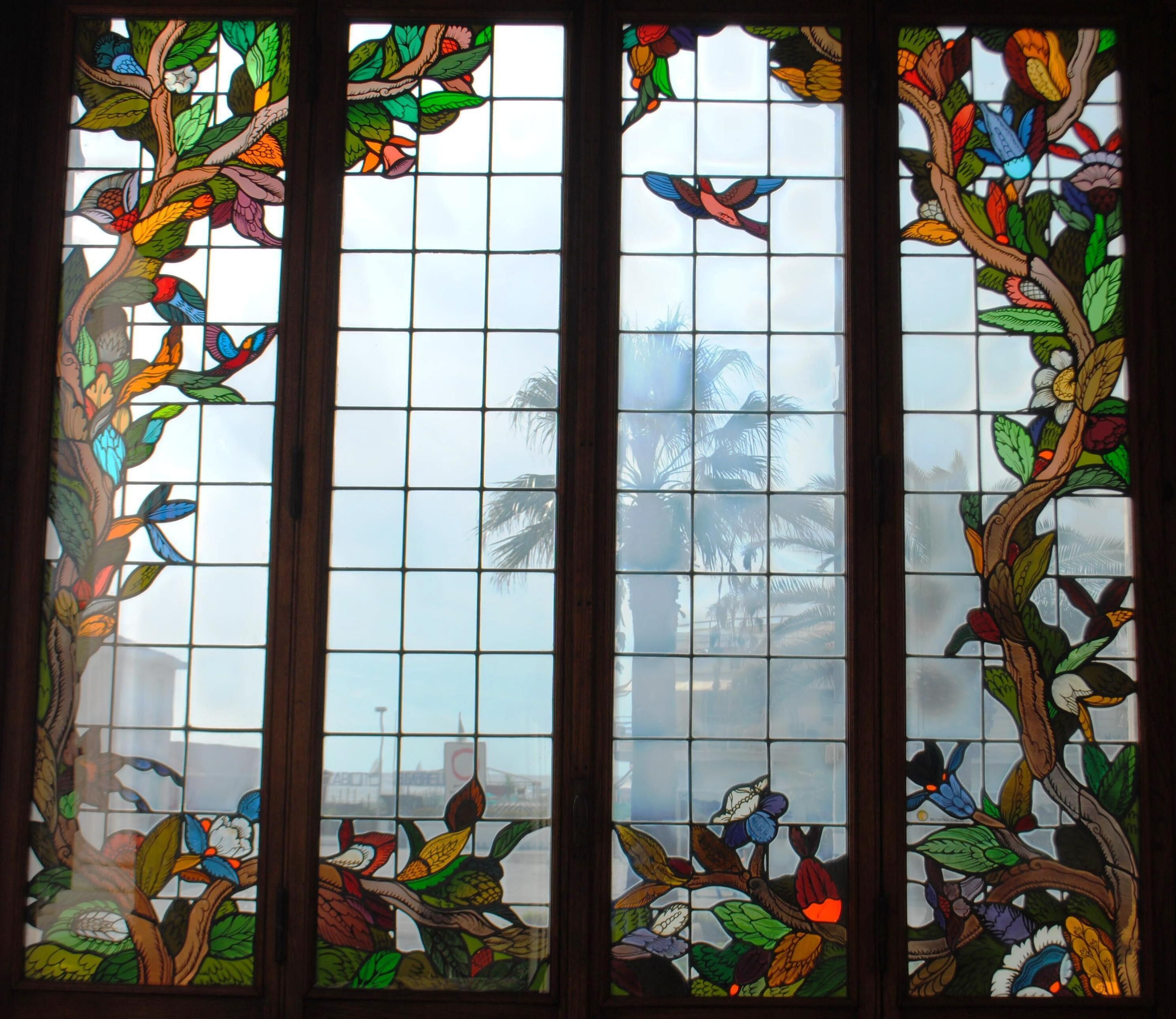 A stained glass window with a tropical design, featuring birds and foliage.