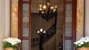 Una imponente escalera conduce a una puerta ornamentada con una araña.
