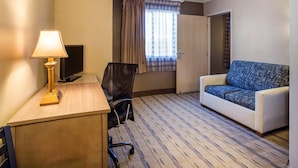 A hotel room with a desk, chair, couch, and a TV. - Quality Inn Moriarty (Moriarty)