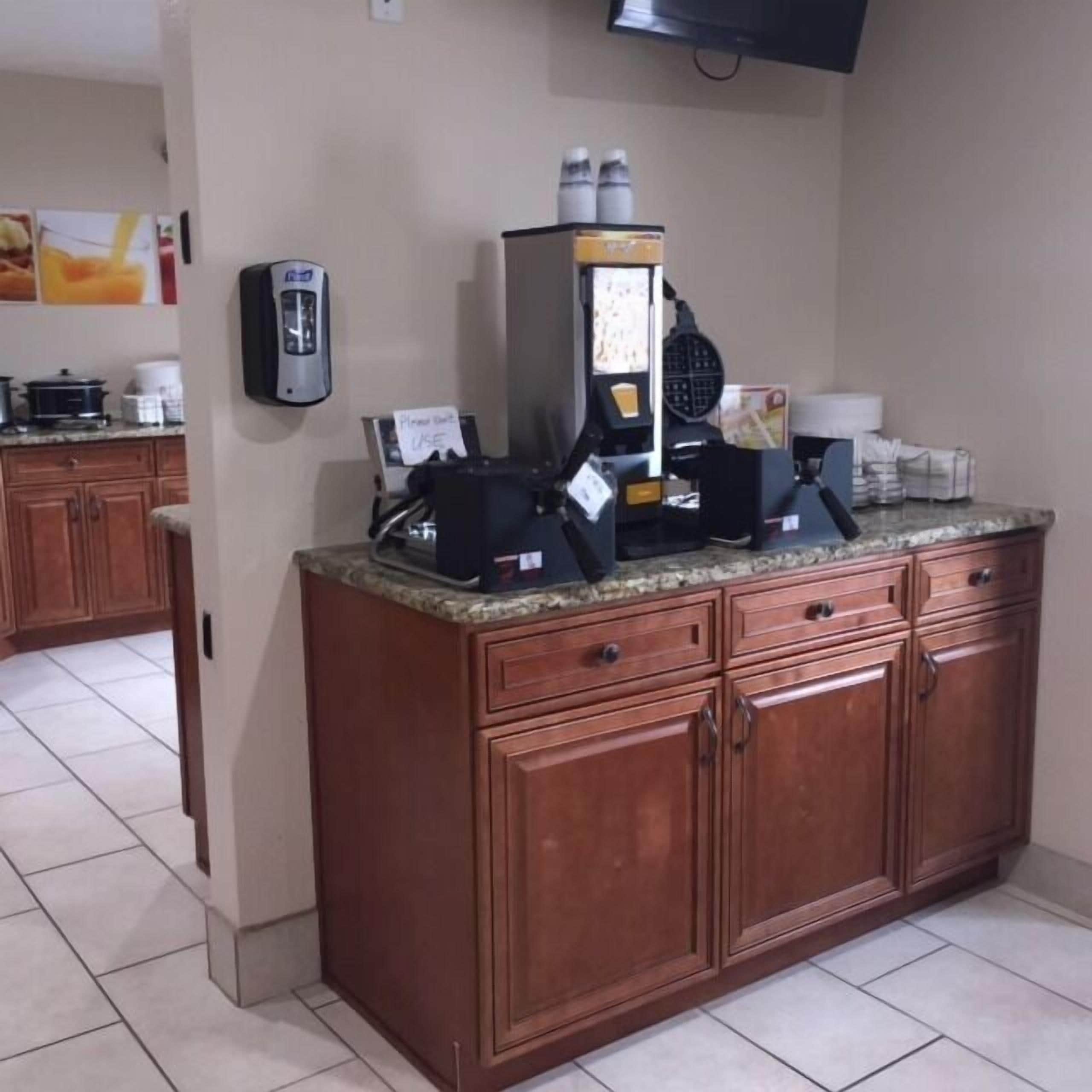 A kitchen with a coffee machine, a microwave, and a toaster. There are cabinets and a countertop.