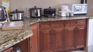A kitchen with granite countertops, wooden cabinets, a microwave, a slow cooker, and a toaster. - Quality Inn Moriarty (Moriarty)