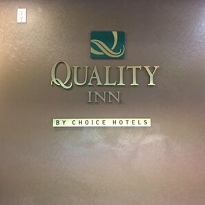 A wall with a logo and text reading "QUALITY INN BY CHOICE HOTELS".