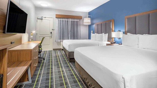 A hotel room with two beds, a desk, a flat-screen TV, a desk lamp, and a window with curtains. - Quality Inn & Suites Livermore Wine Country (Livermore)