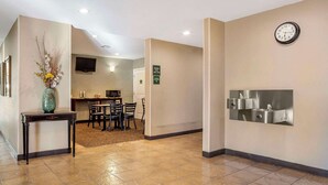 A hotel lobby with a dining area, a clock, and a wall-mounted sink. - Quality Inn & Suites Livermore Wine Country (Livermore)