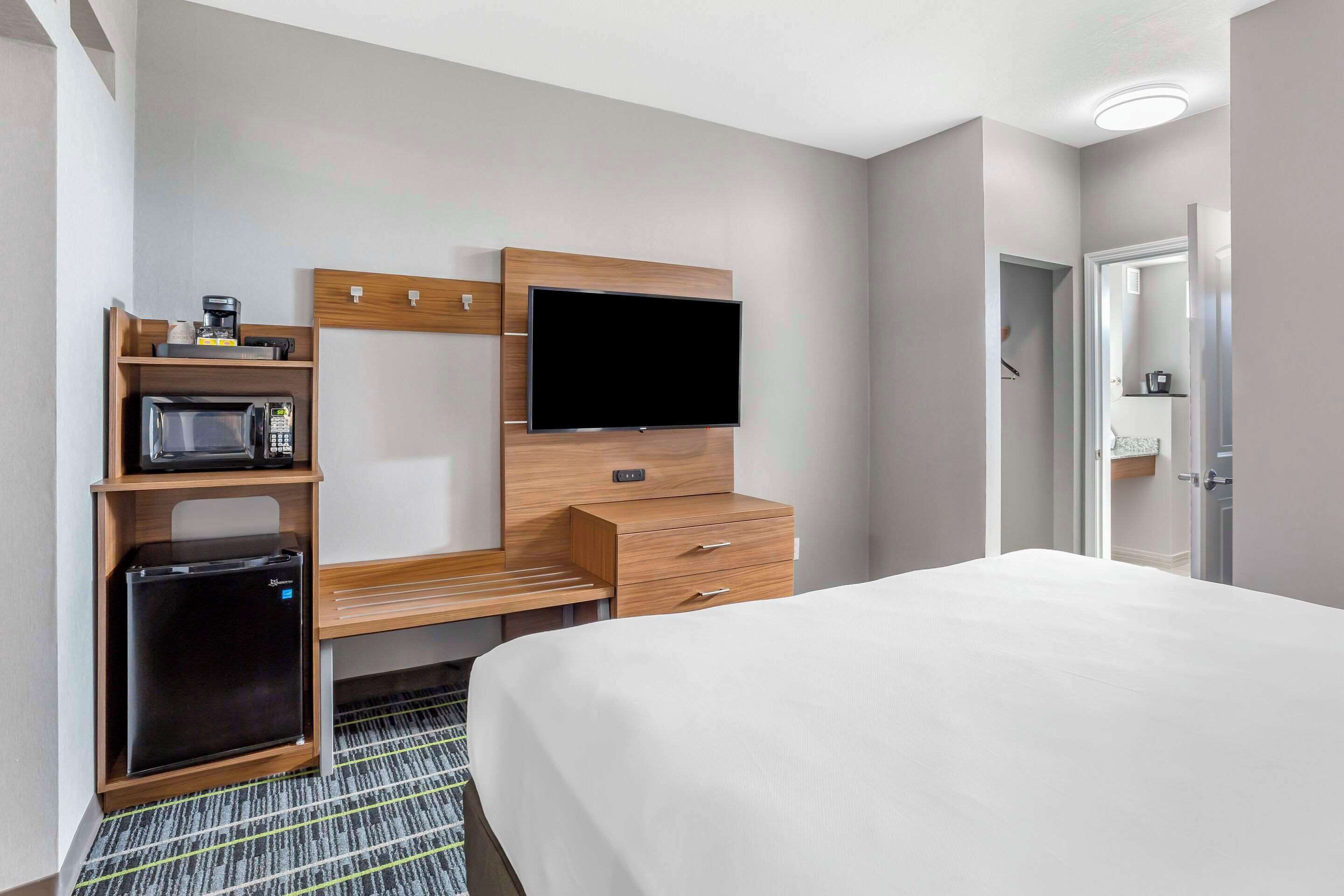 Une chambre d’hôtel équipée d’un lit, d’un téléviseur fixé au mur, d’un four à micro-ondes et d’un réfrigérateur.