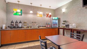 A hotel breakfast area with wooden cabinets, a coffee machine, a refrigerator, and a dining table with chairs. - Quality Inn & Suites Livermore Wine Country (Livermore)