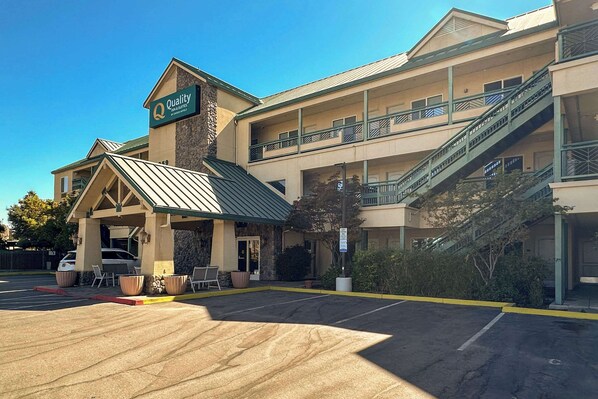 A hotel with a covered entrance, outdoor seating, and a staircase leading to the upper level.