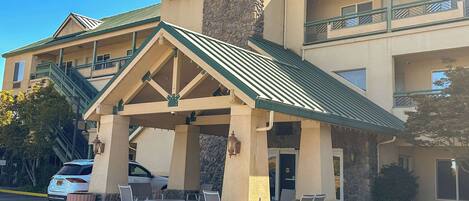A hotel with a covered outdoor seating area, a stone facade, and a sign indicating it is a Choice Hotels property.
