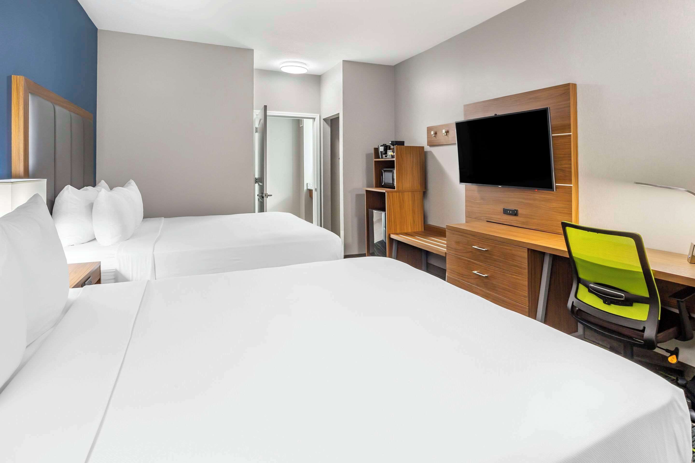 Habitació d'hotel amb dos llits, un escriptori amb cadira, televisió i minibar.
