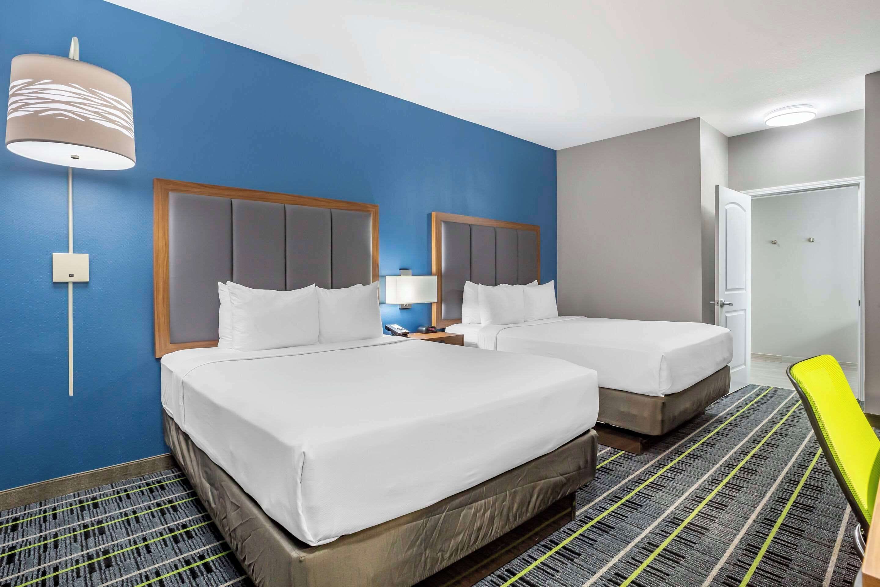 Een hotelkamer met twee bedden, een nachtkastje, een lamp en een deur.