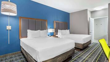 Een hotelkamer met twee bedden, een nachtkastje, een lamp en een deur.