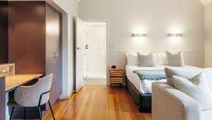 A modern bedroom with a bed, bedside tables, a desk, and a chair. - Freycinet Lodge (Coles Bay)