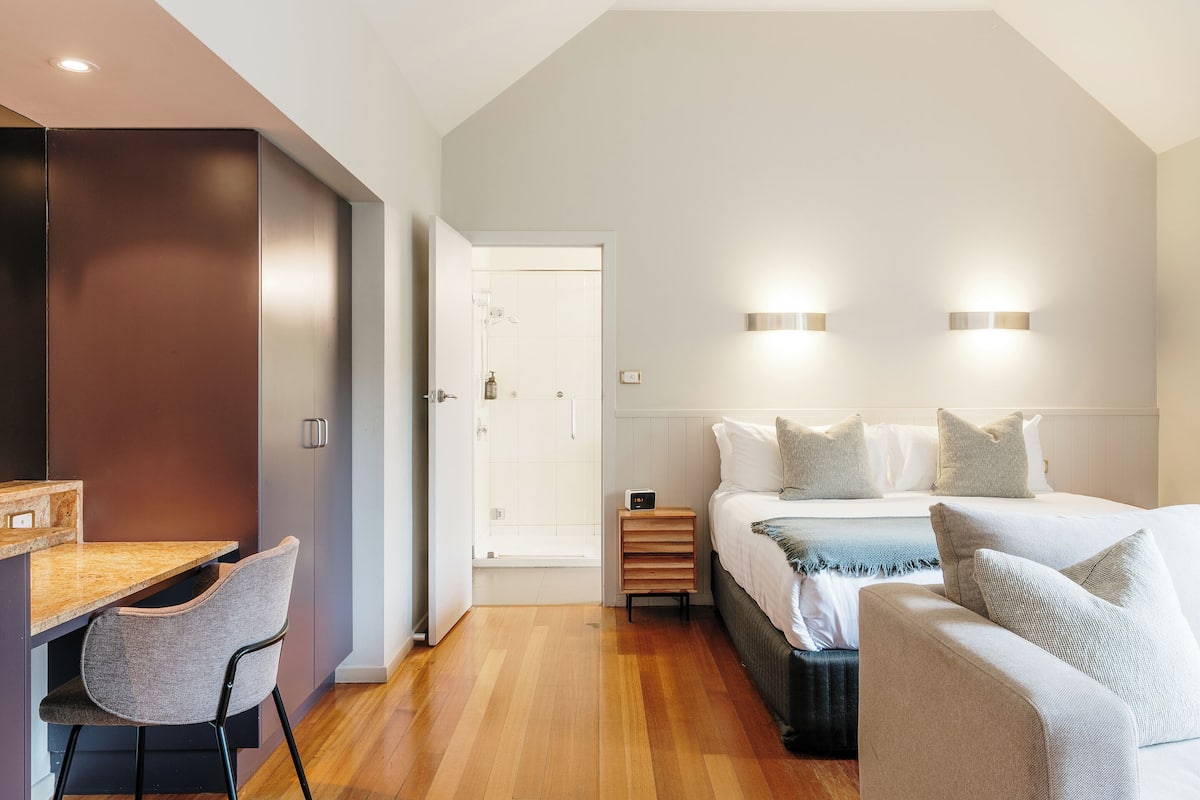Un dormitorio moderno con cama, mesitas de noche, un escritorio y una silla.