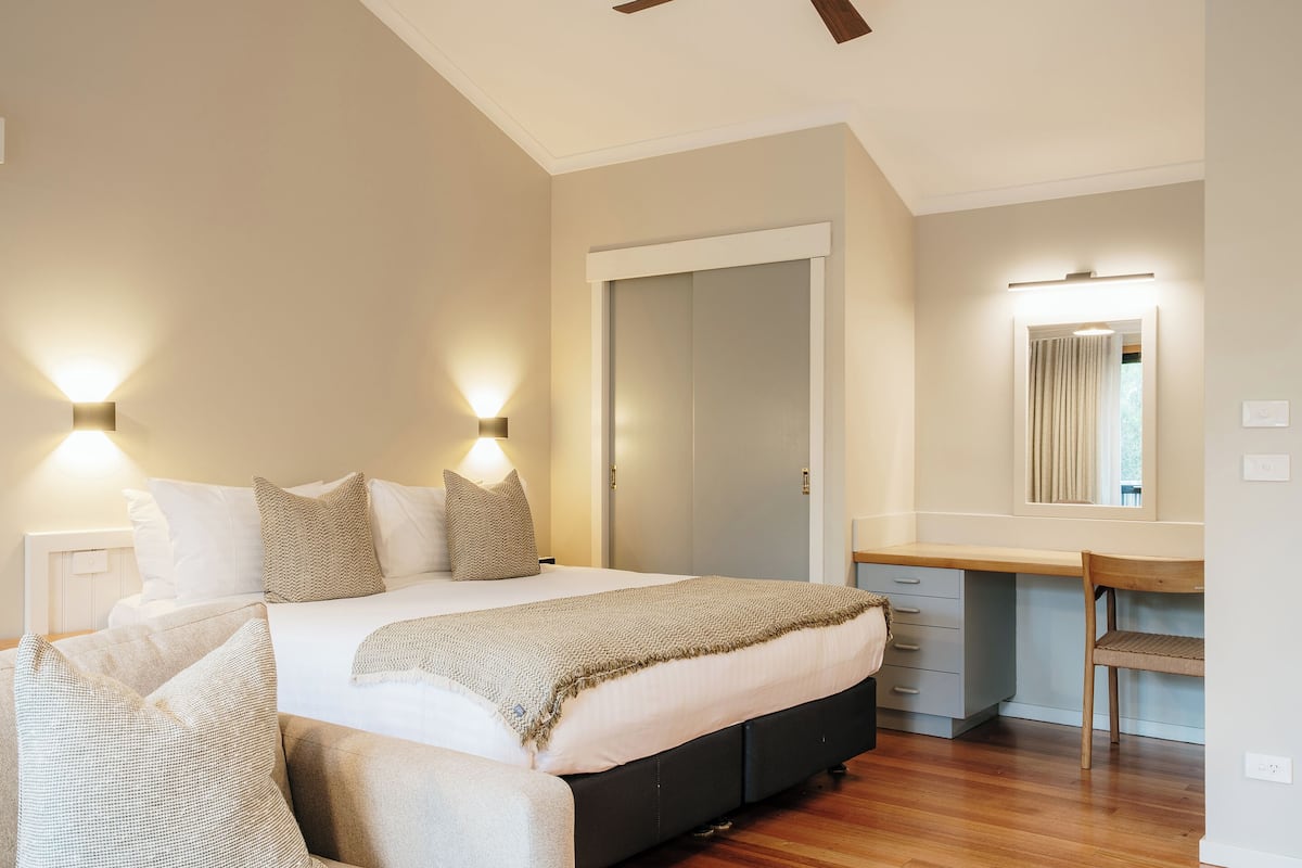 Un dormitorio con cama, mesitas de noche, escritorio y espejo.