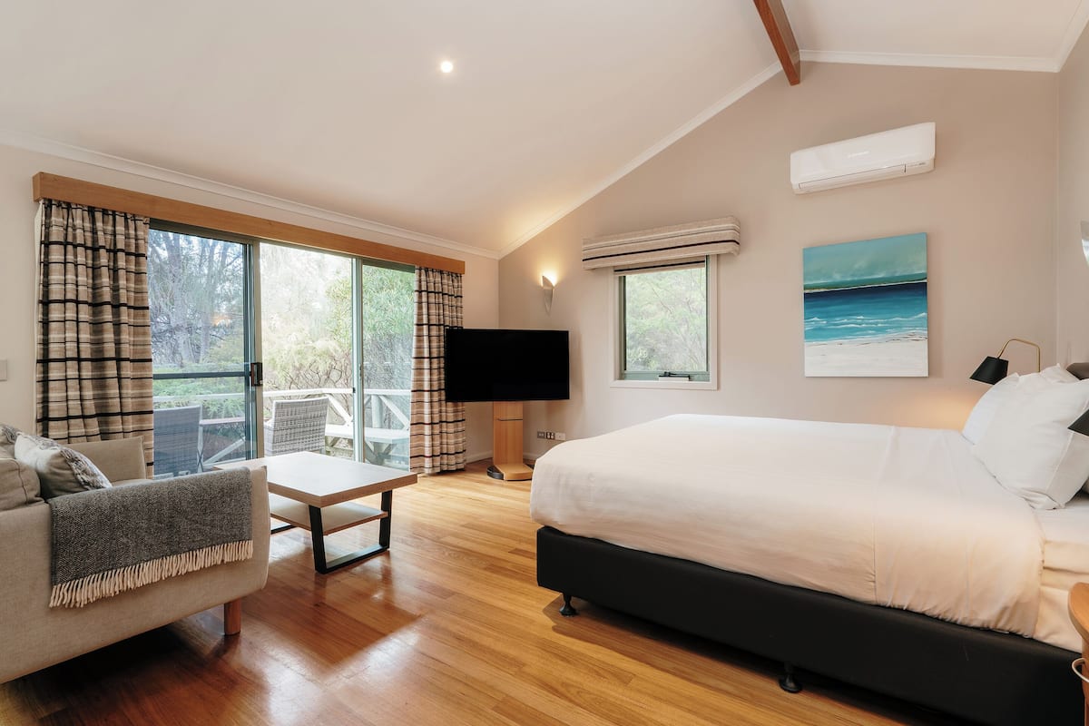 Un dormitorio con una cama grande, televisión, escritorio y vistas al exterior.