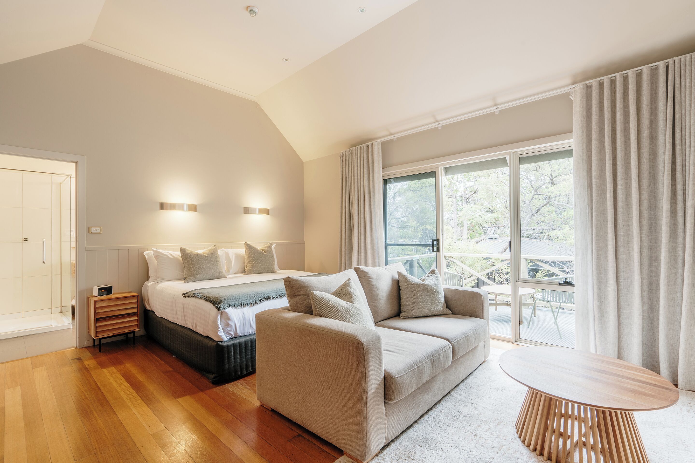 A modern bedroom with a bed, a sofa, and a table.