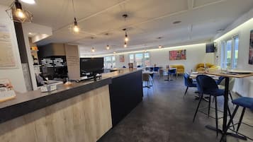 Un restaurante moderno con un mostrador central, varias áreas de estar e iluminación colgante.