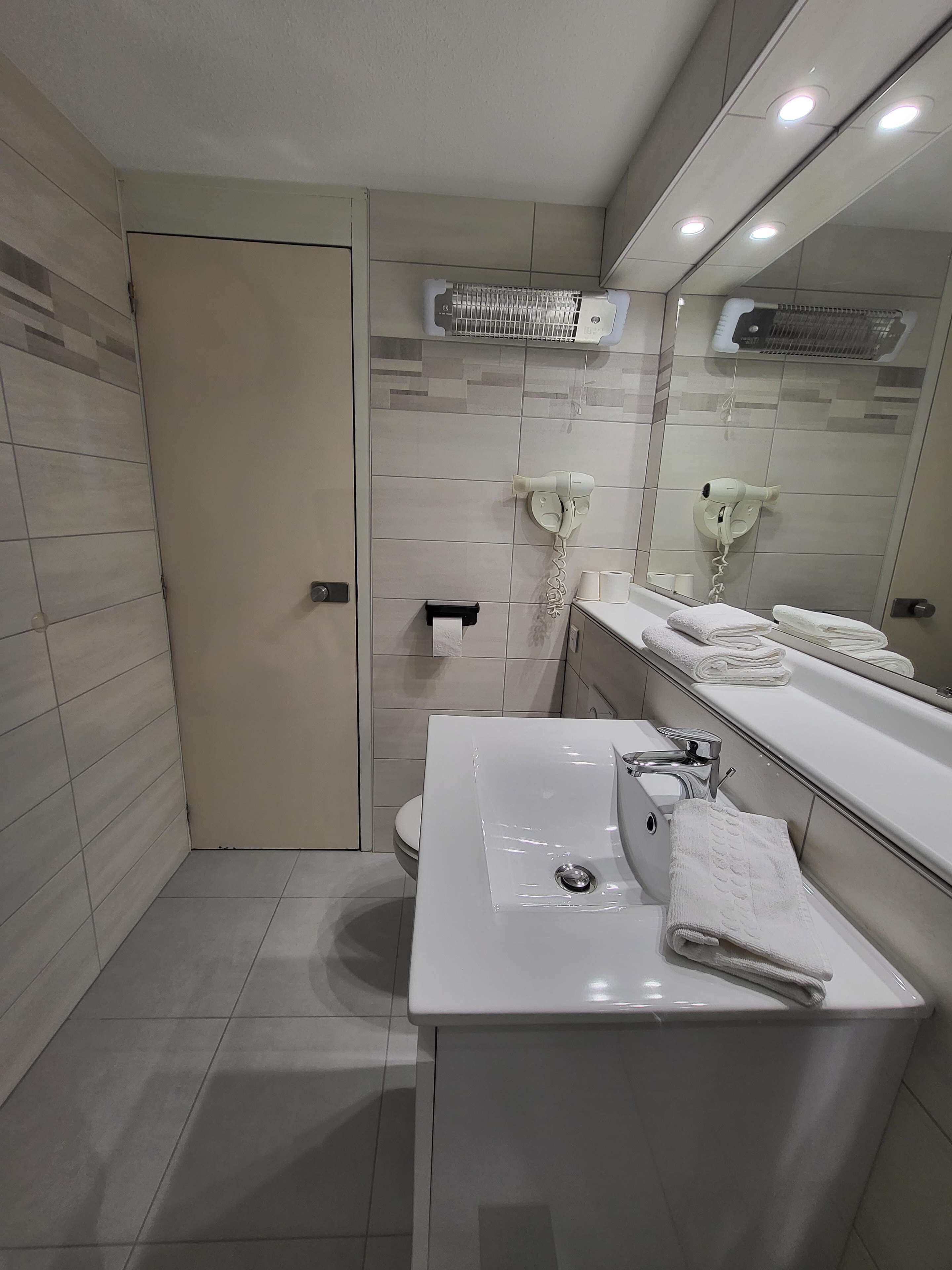 A modern bathroom with a white sink, mirror, and towel rack.