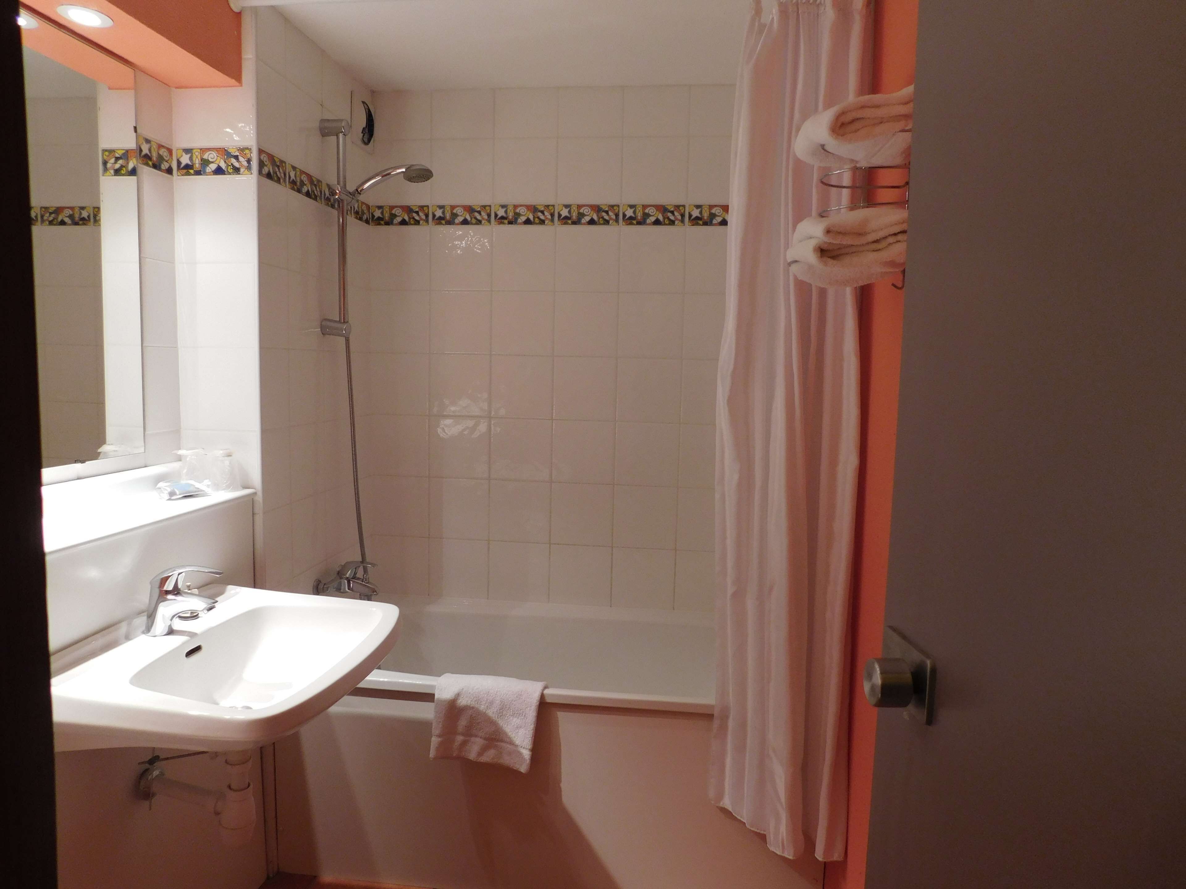 A bathroom with a sink, mirror, shower, and a towel rack.