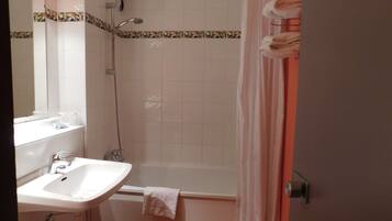 A bathroom with a sink, mirror, shower, and a towel rack.
