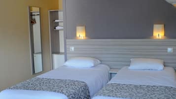 A hotel room with two beds, a mirror, and two wall-mounted lamps.