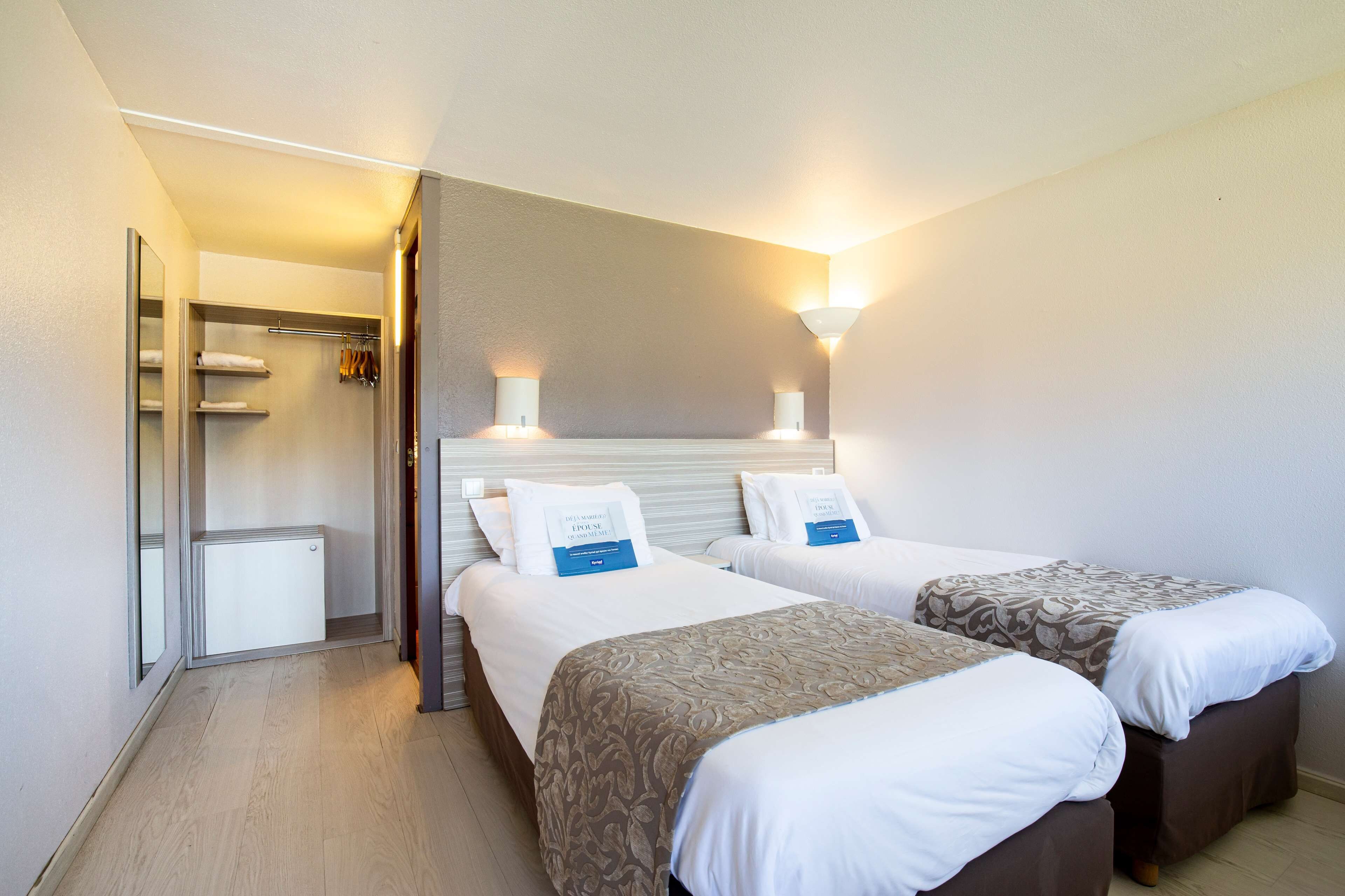 Une chambre d’hôtel avec deux lits, une armoire et un miroir.
