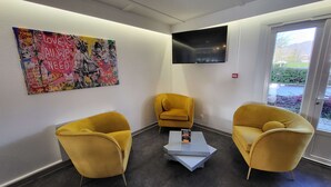 Een receptiezone met een kleurrijke graffiti-muur, een flatscreen-televisie en twee gele stoelen met een salontafel in het midden.