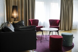 Una sala de estar moderna con un sofá, dos sillones rojos, una mesita redonda y una lámpara.