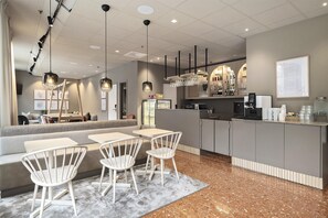 A modern cafe with a bar area, seating with white chairs, and a granite-tiled floor.