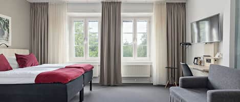 Una habitación de hotel con cama, escritorio, silla y televisión.