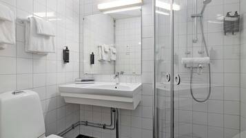 Un baño moderno con lavamanos blanco, espejo y cabina de ducha de vidrio.