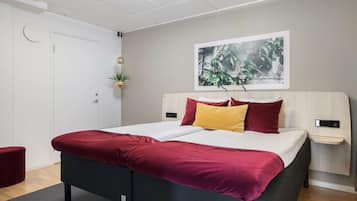 Een moderne hotelkamer met een groot bed, een nachtkastje, een aan de wand bevestigde plant en een ingelijst schilderij.