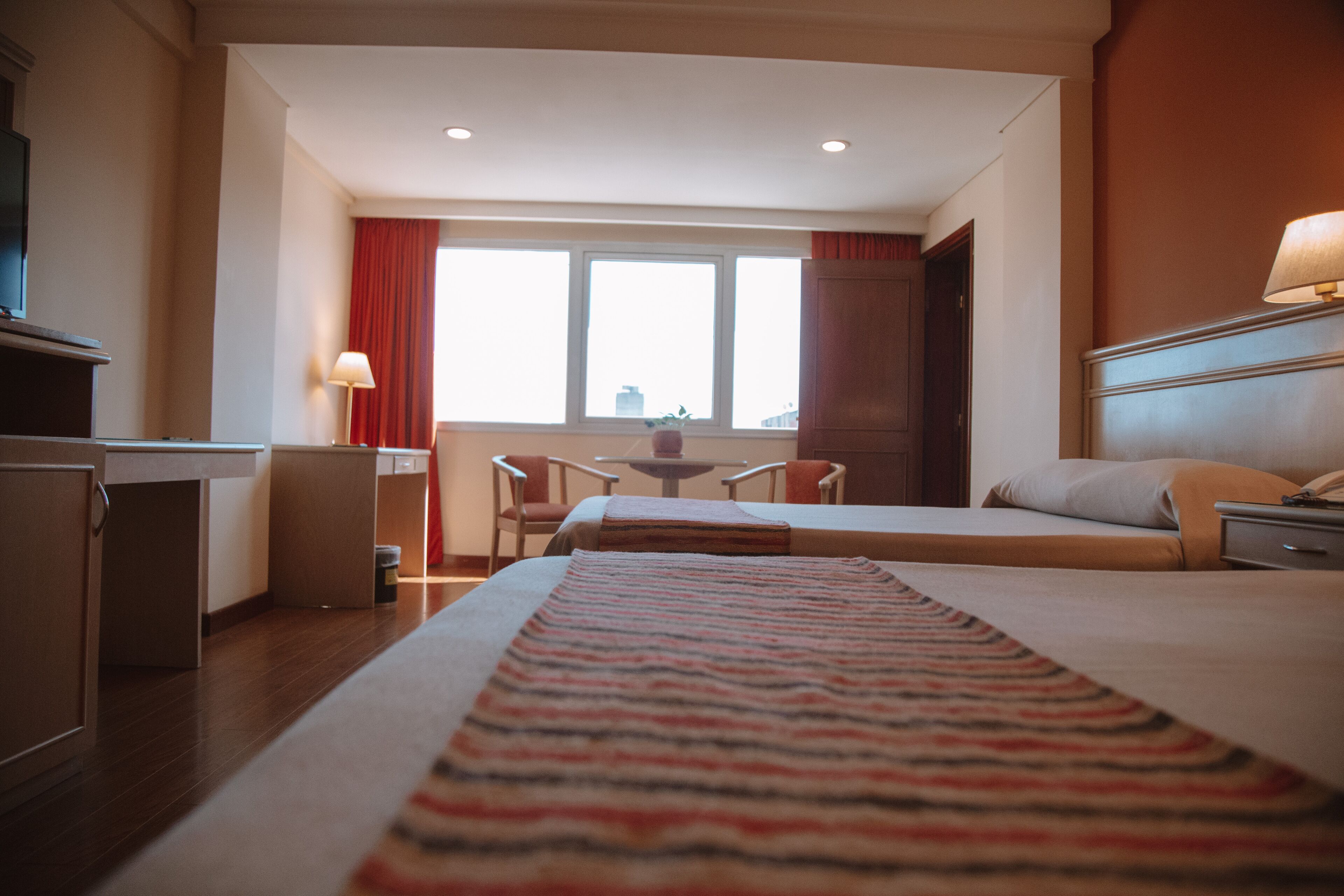 A hotel room with a bed, a desk, a chair, and a window.