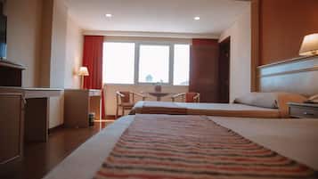A hotel room with a bed, a desk, a chair, and a window.