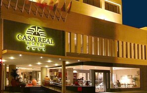 The exterior of Casa Real Hotel with a prominent sign, a covered entrance area, and visible interior spaces including a dining area.
