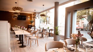 A modern restaurant with wooden panel walls, pendant lighting, and a view of the street through large windows. - Casa Real (Salta)