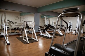 A gym with various exercise machines and mats on the floor.