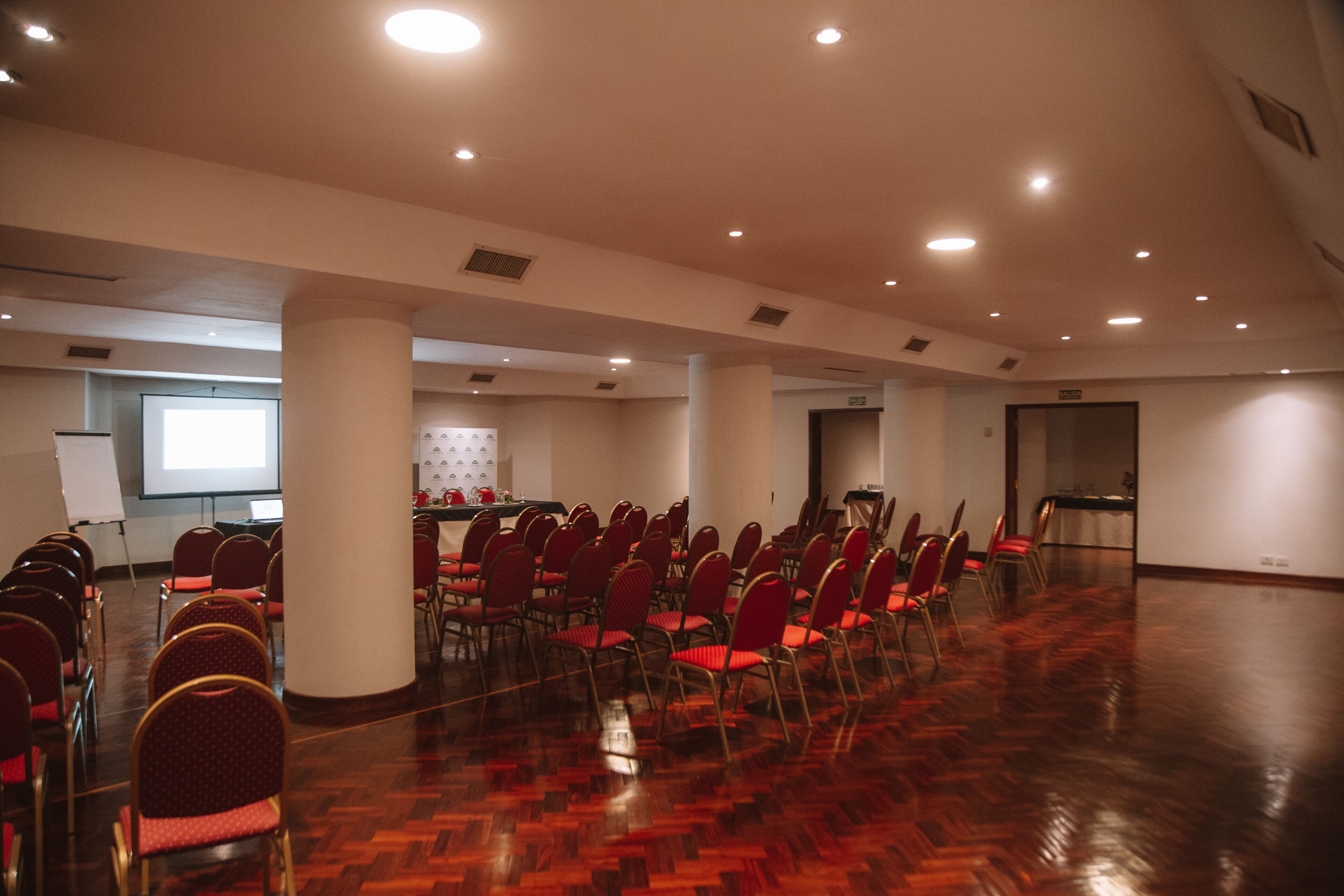 A conference room with rows of chairs, a projection screen, and a podium.