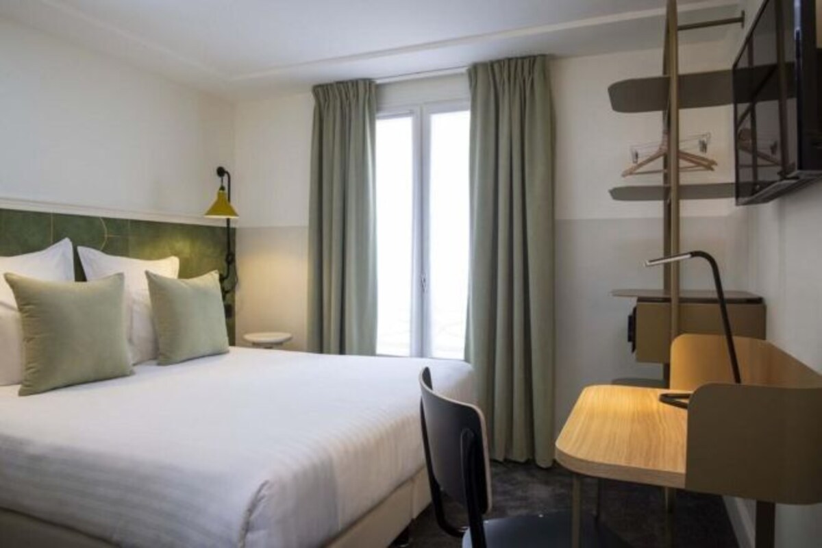 A hotel room with a bed, a desk, and a chair.